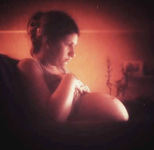 Pregnant woman sitting in the dark.